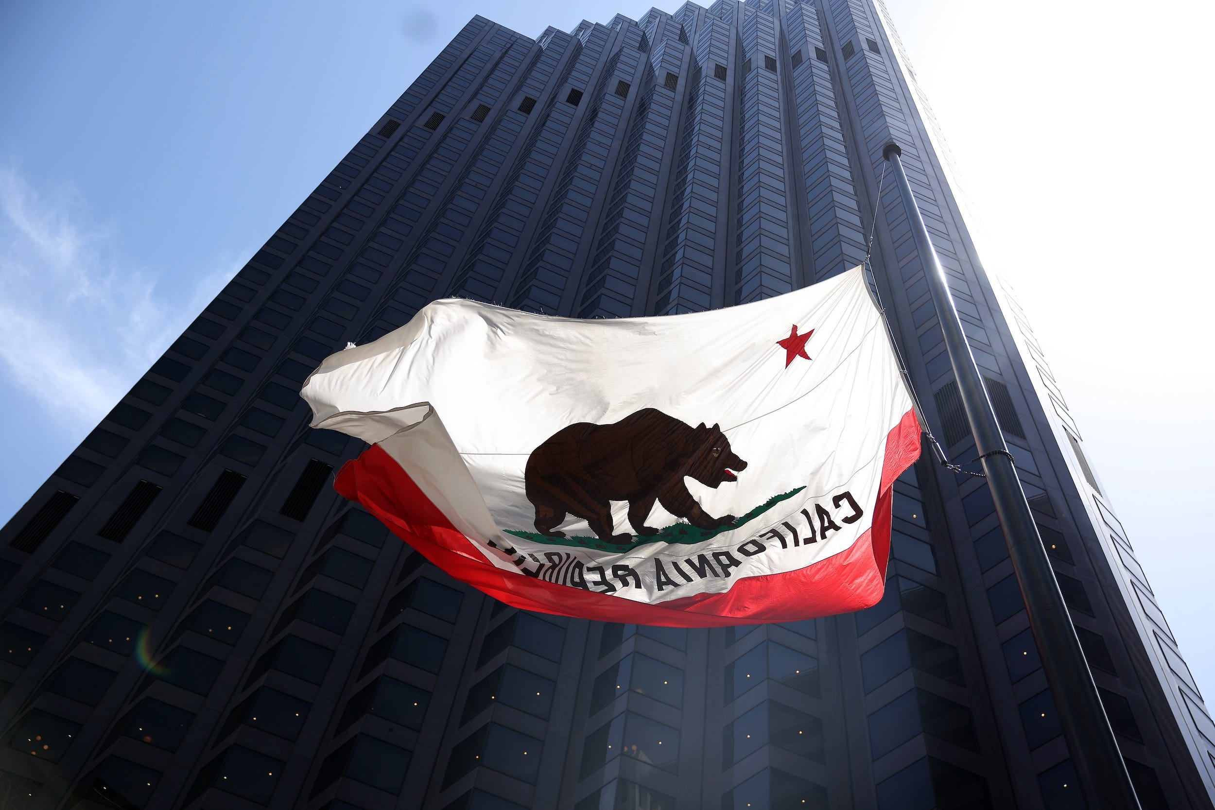 A California flag flies in front of a building on California Street in San Francisco