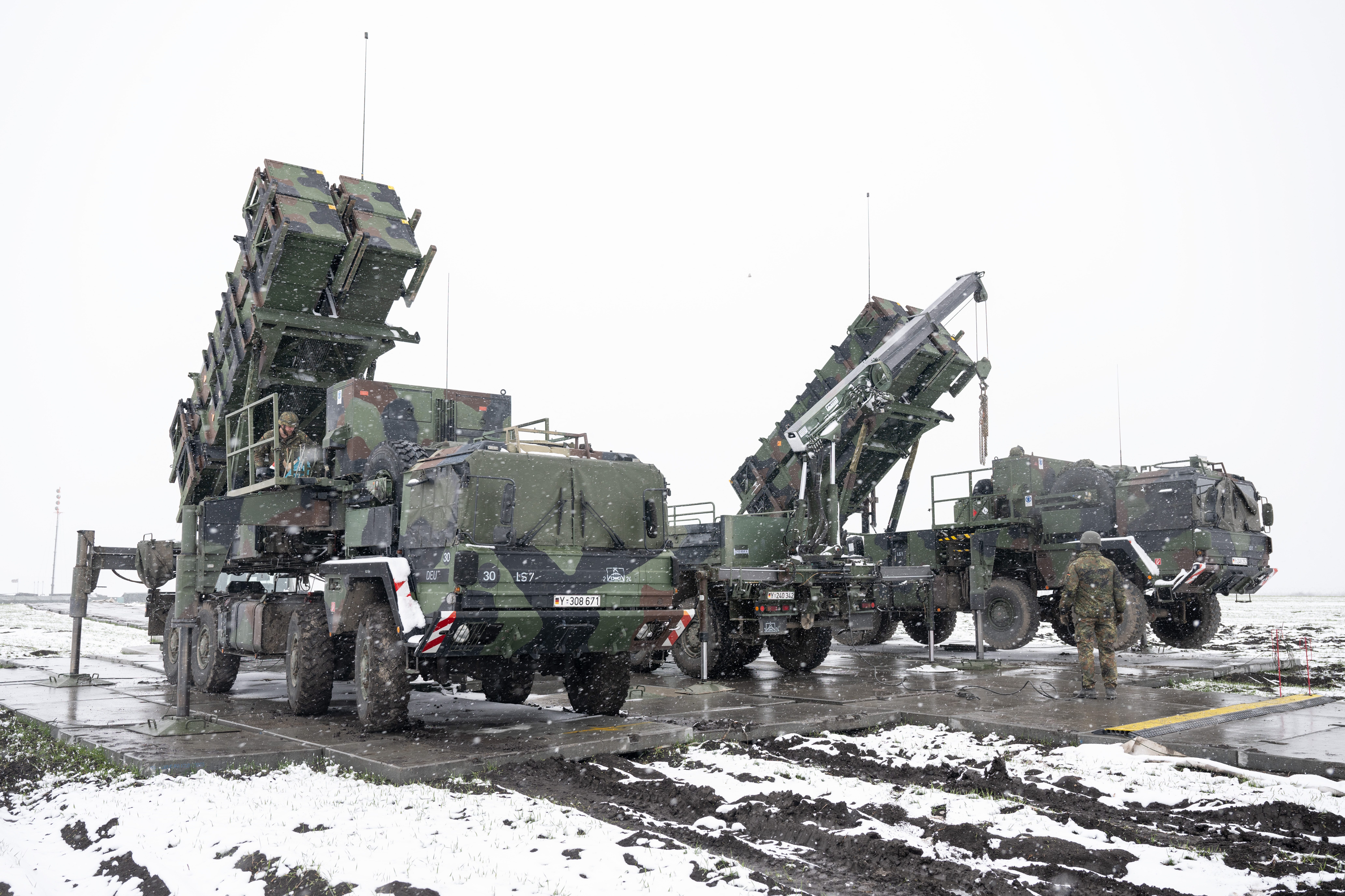 Bundeswehr soldiers work on a crane between trailers with launchers for guided missiles of the Patriot air defense system.