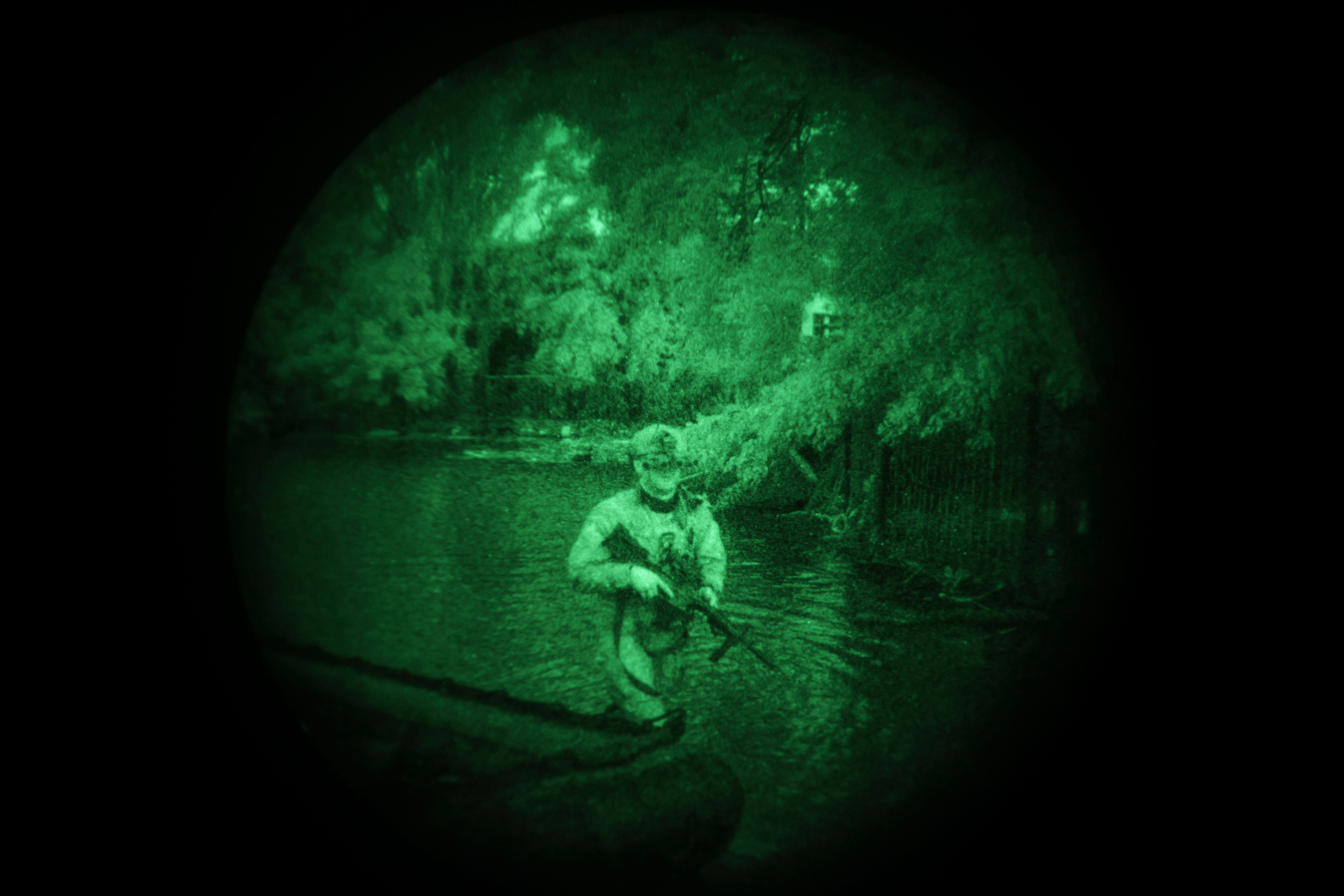 A Ukrainian special forces soldier walks in the water at night along the Dnipro River