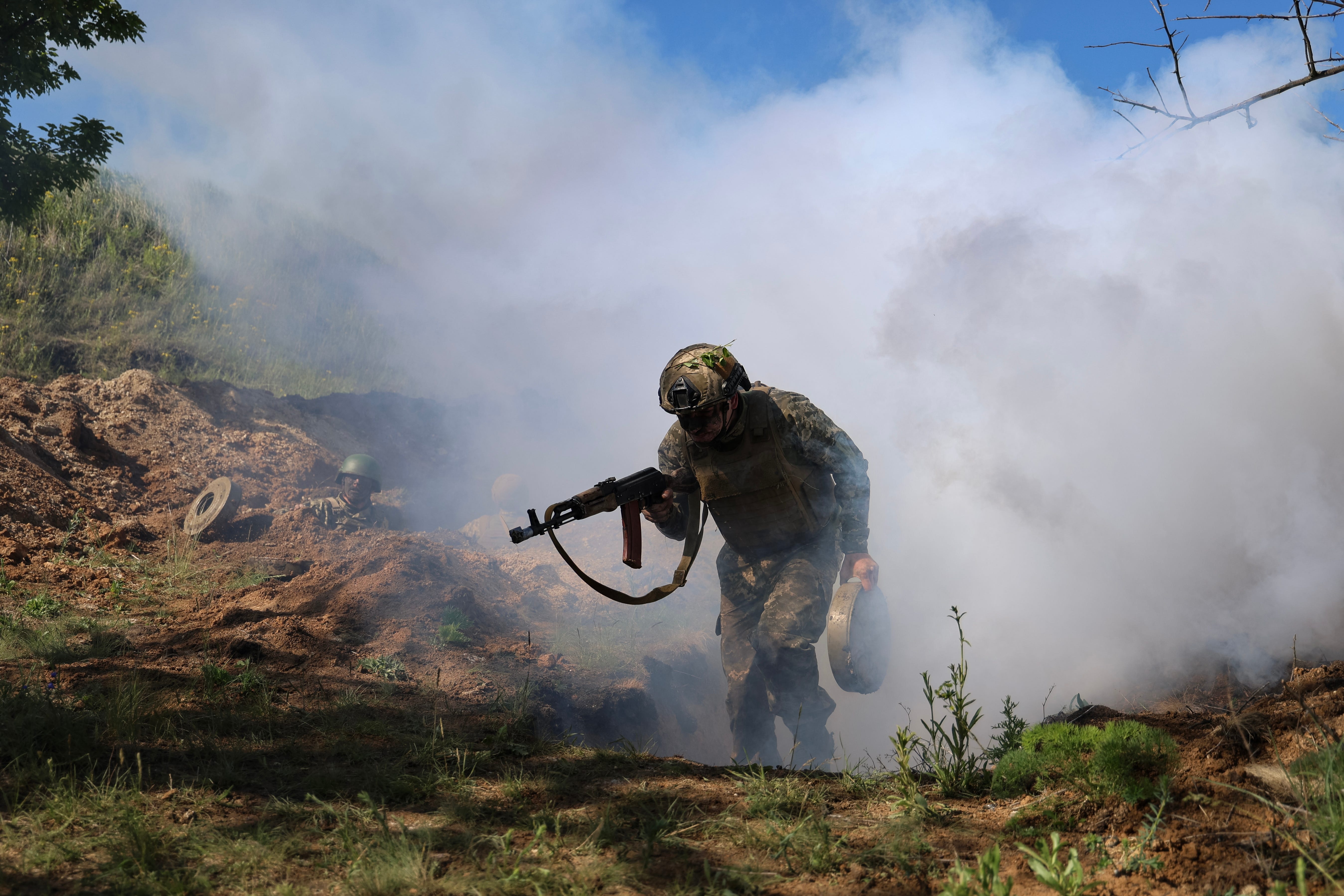UNSPECIFIED, UKRAINE - MAY 13: Ukrainian Marines of the 37th Marine Brigade run from a trench through a smoke bomb overcoming an obstacle course during military exercises on May 13, 2025 in an unspecified region in Ukraine.