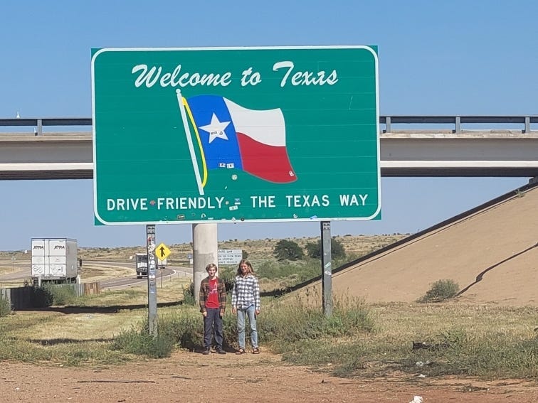 The Koster children under a "Welcome to Texas" road sign.