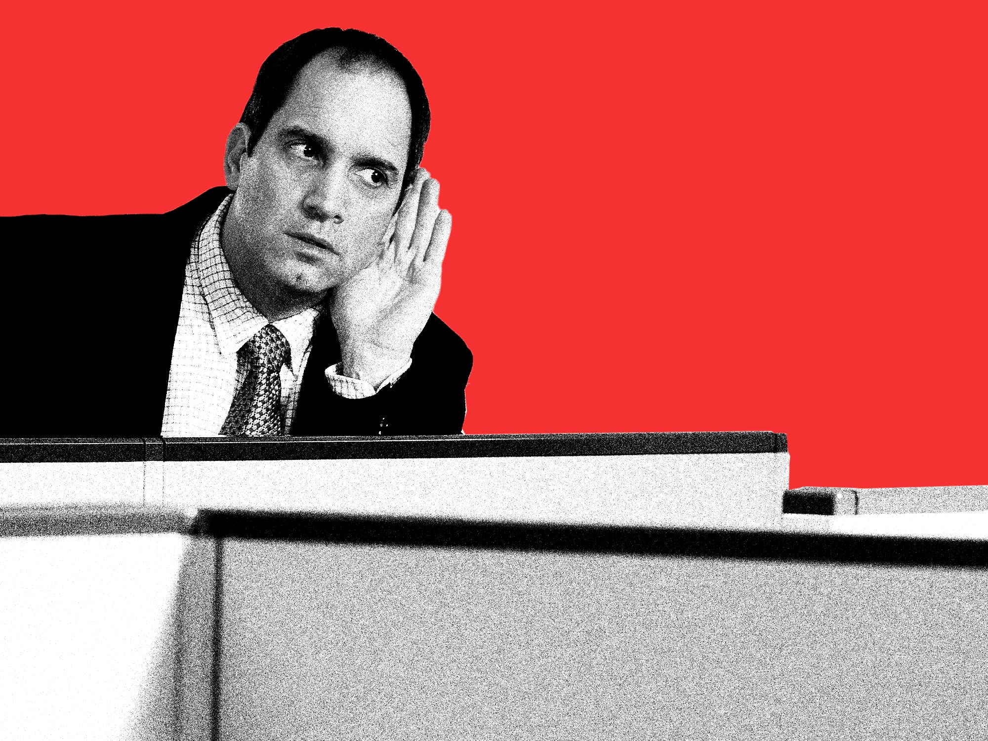 Man with hand on his ear in a cubicle