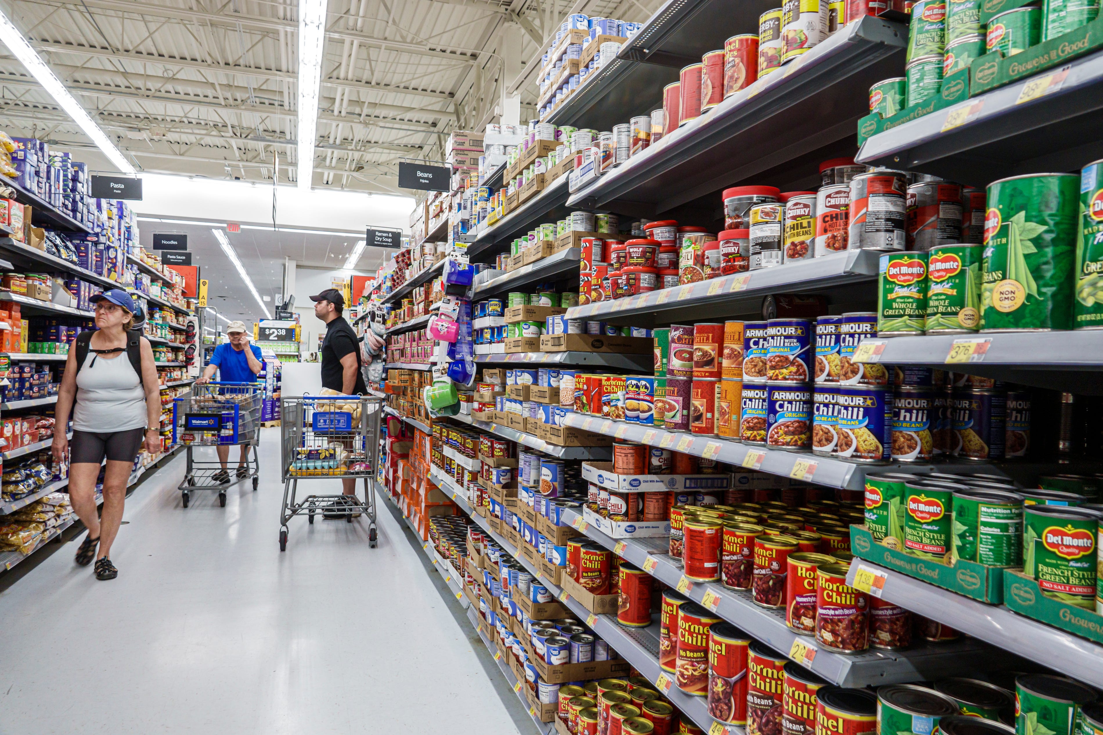 Walmart customers shop the aisles stocked with Del Monte, Armour and Hormel canned goods.