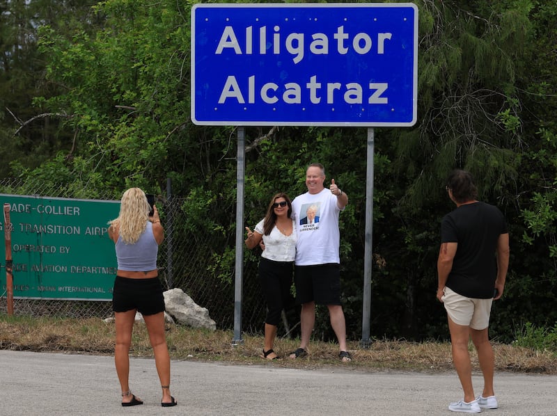 Maricel Walsh and Paul Shobert have a selfie taken by Lisa Uhrich in front of the Alligator Alcatraz sign