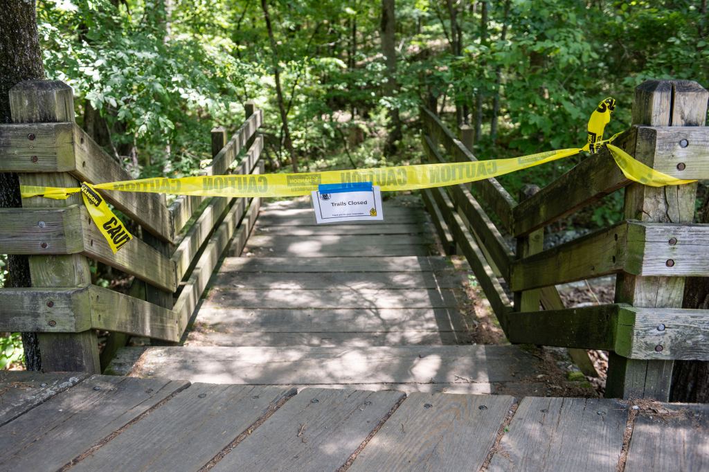 Police tape block the trail head to the Devil's Den trail at Devil's Den State Park on July 28, 2025.