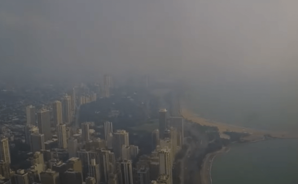 Aerial view of a hazy city skyline and coastline.