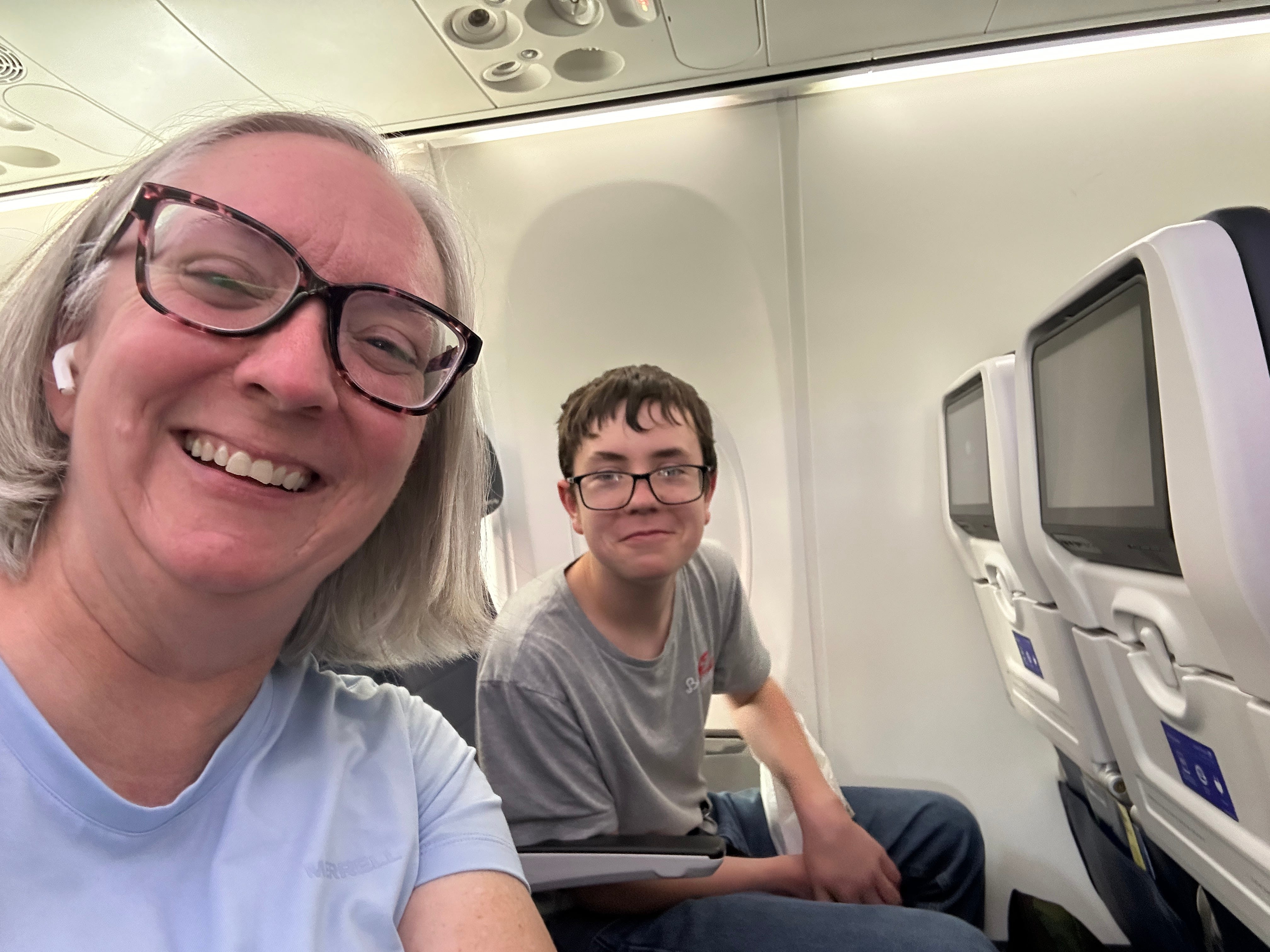 Kate and her son smile for a photo while sitting on a plane.