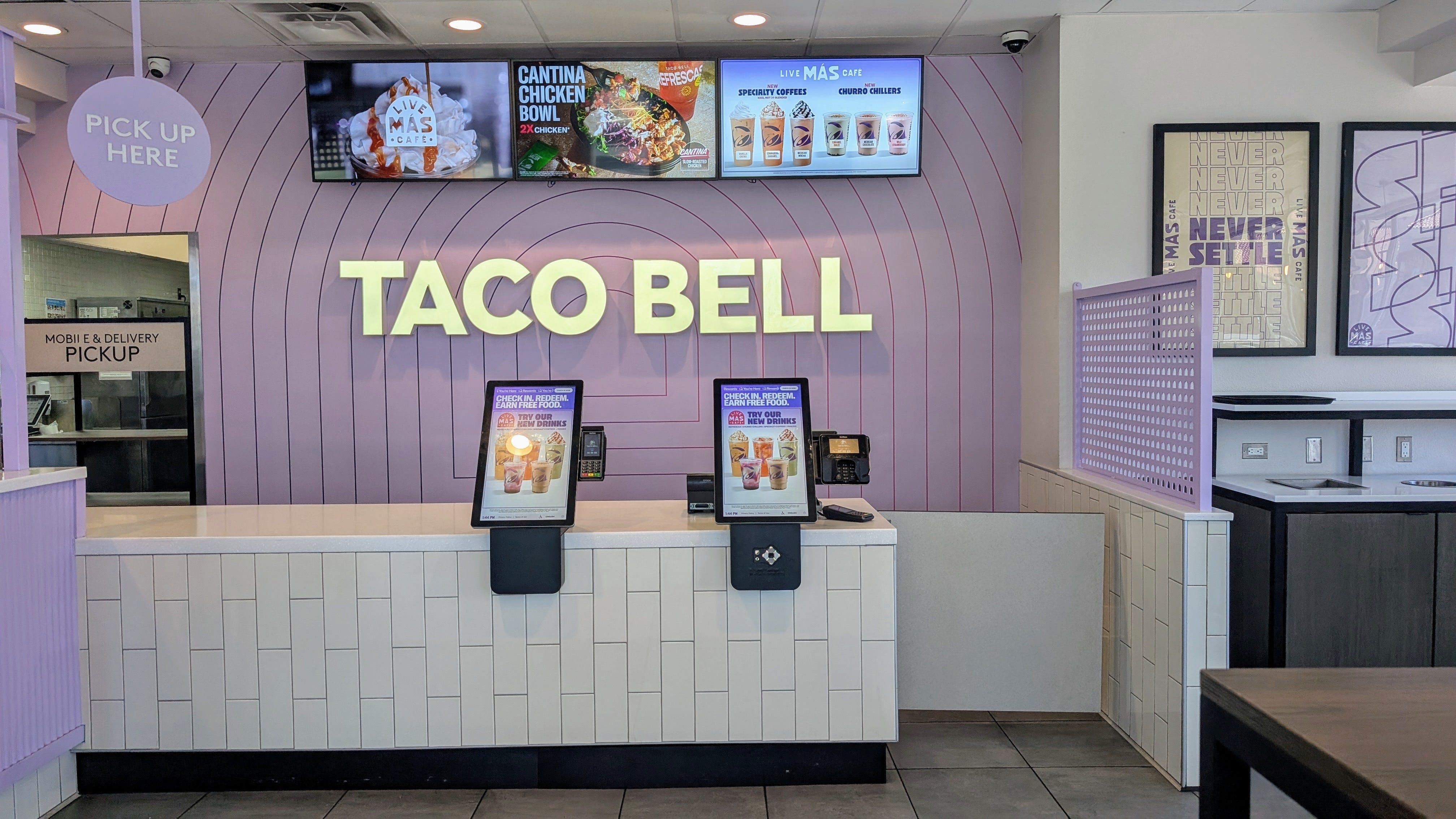Light-up Taco Bell sign with two ordering kiosks underneath, menus on screens above