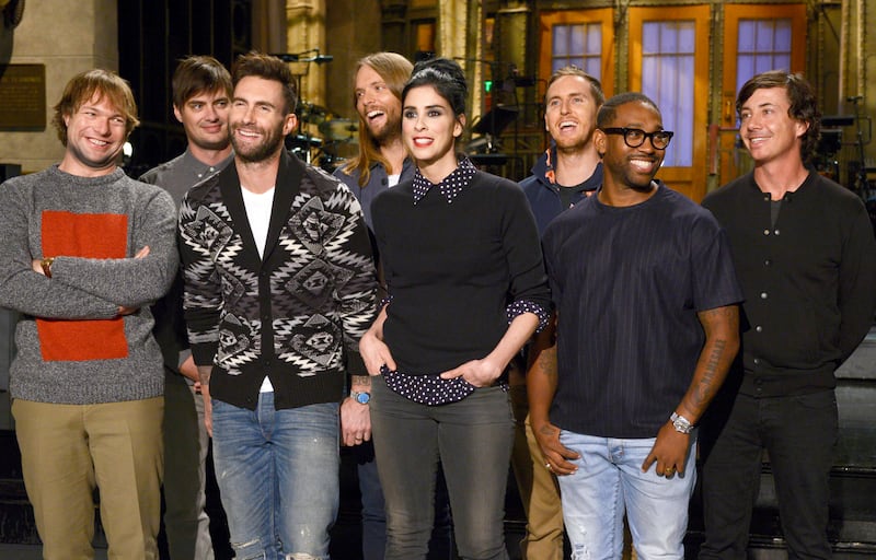 (l-r) Mickey Madden, Adam Levine, James Valentine, Jesse Carmichael, PJ Morton and Matt Flynn of musical guest Maroon 5 pose with comedian Sarah Silverman on Saturday Night Live in 2014.