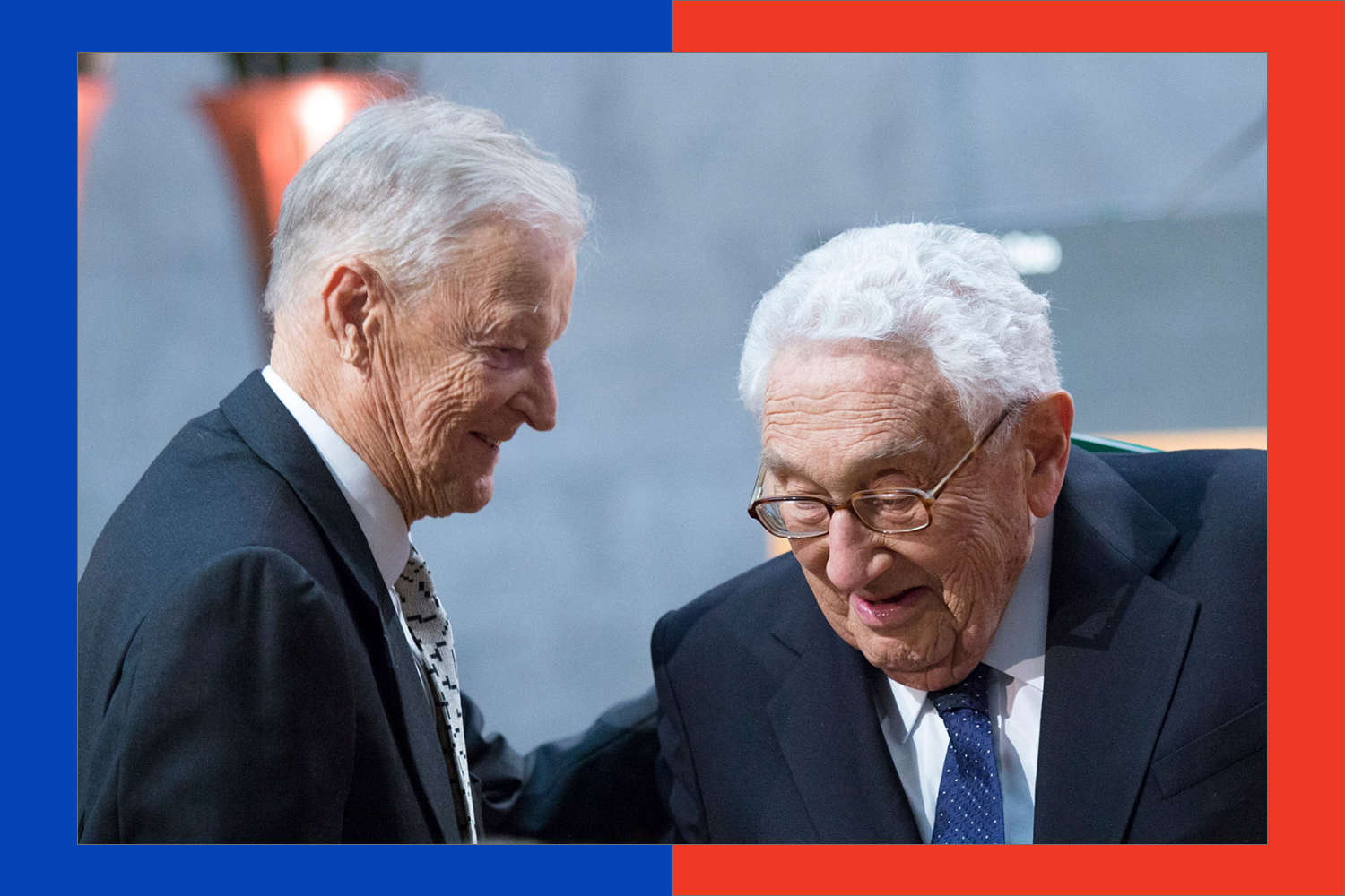 Brzezinski smiles and leans toward Kissnger also smiling as he passes.