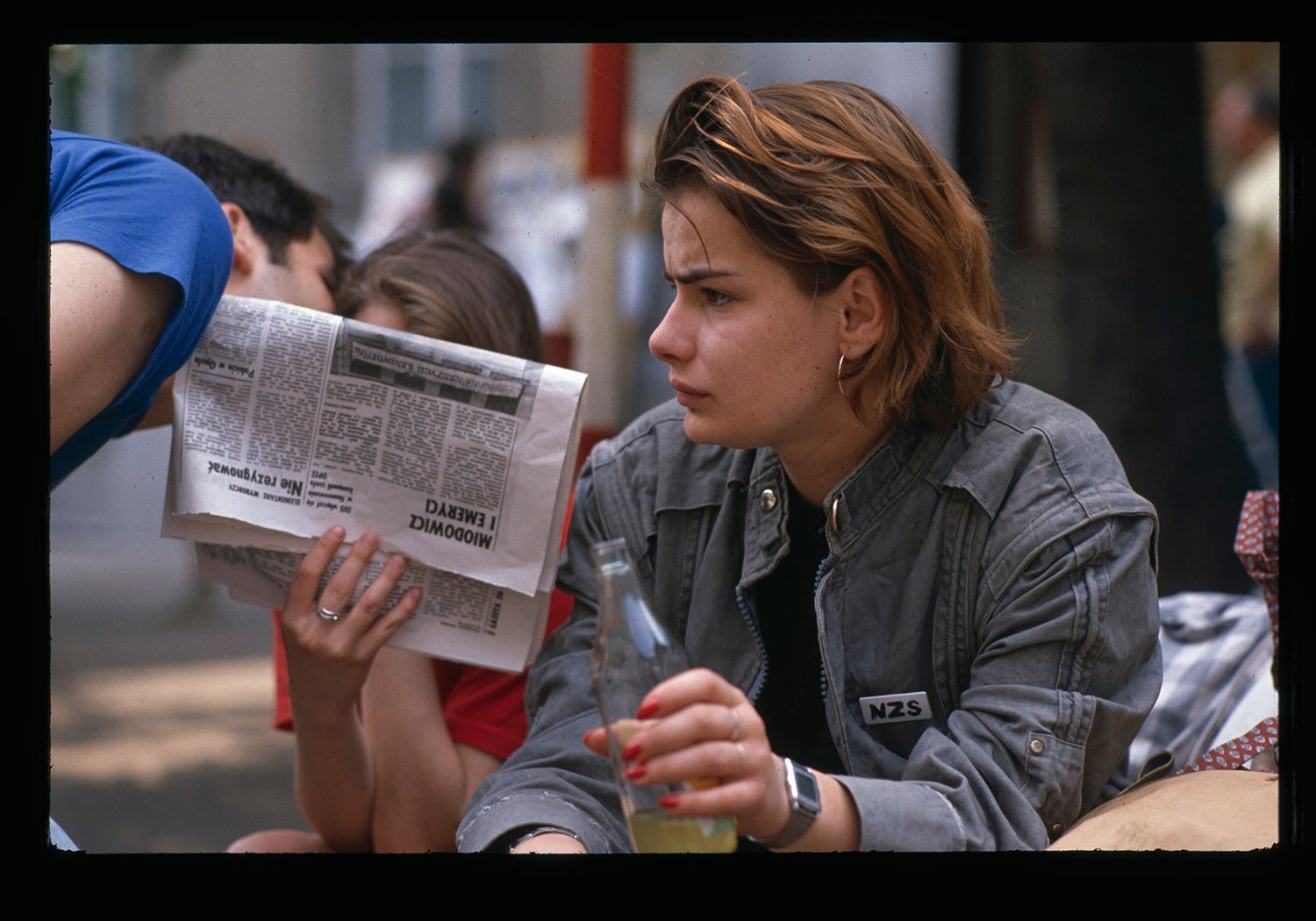 A woman holds a newspaper and a soda bottle during a sit-in
