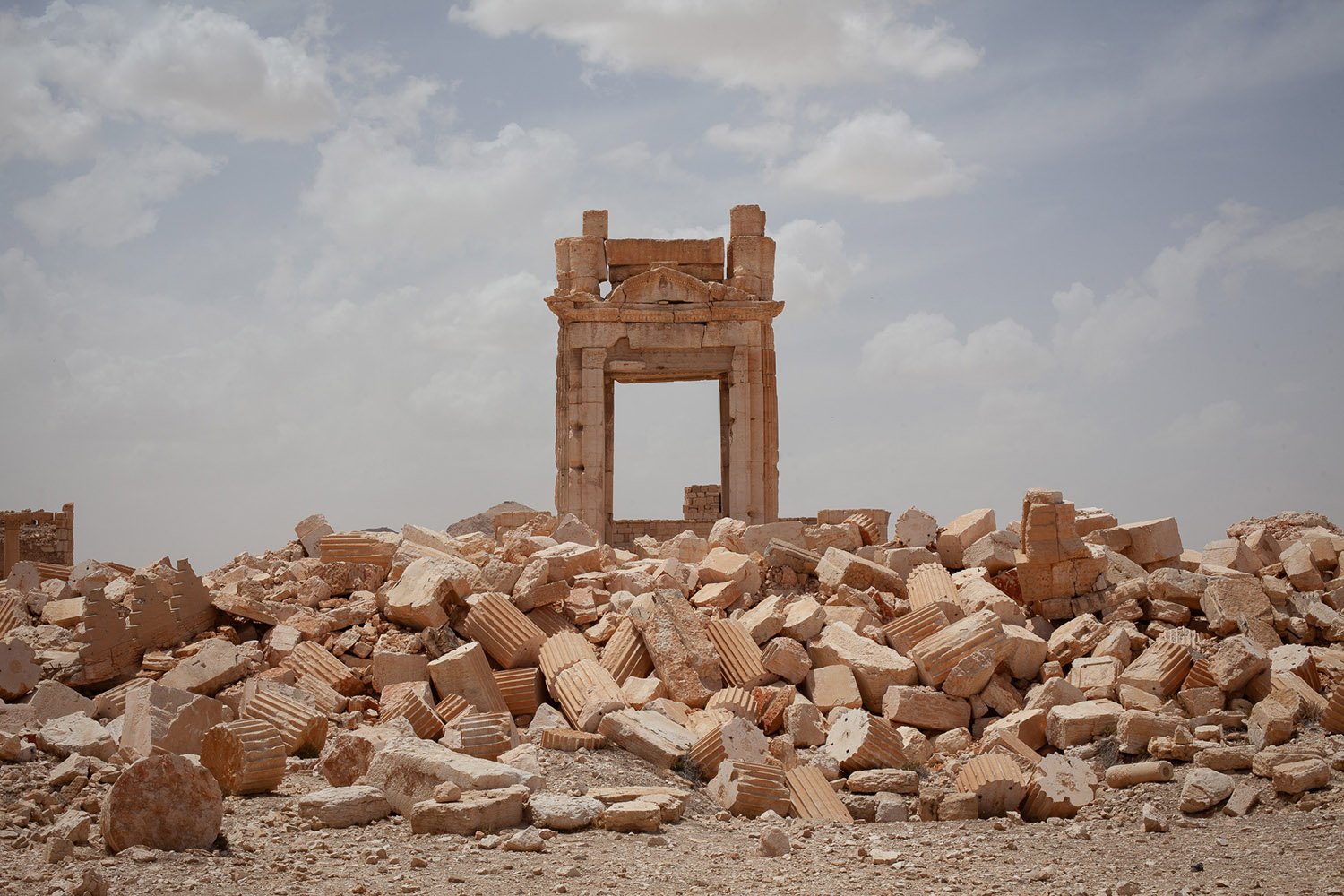An archway atop a pile of rubble and broken columns.