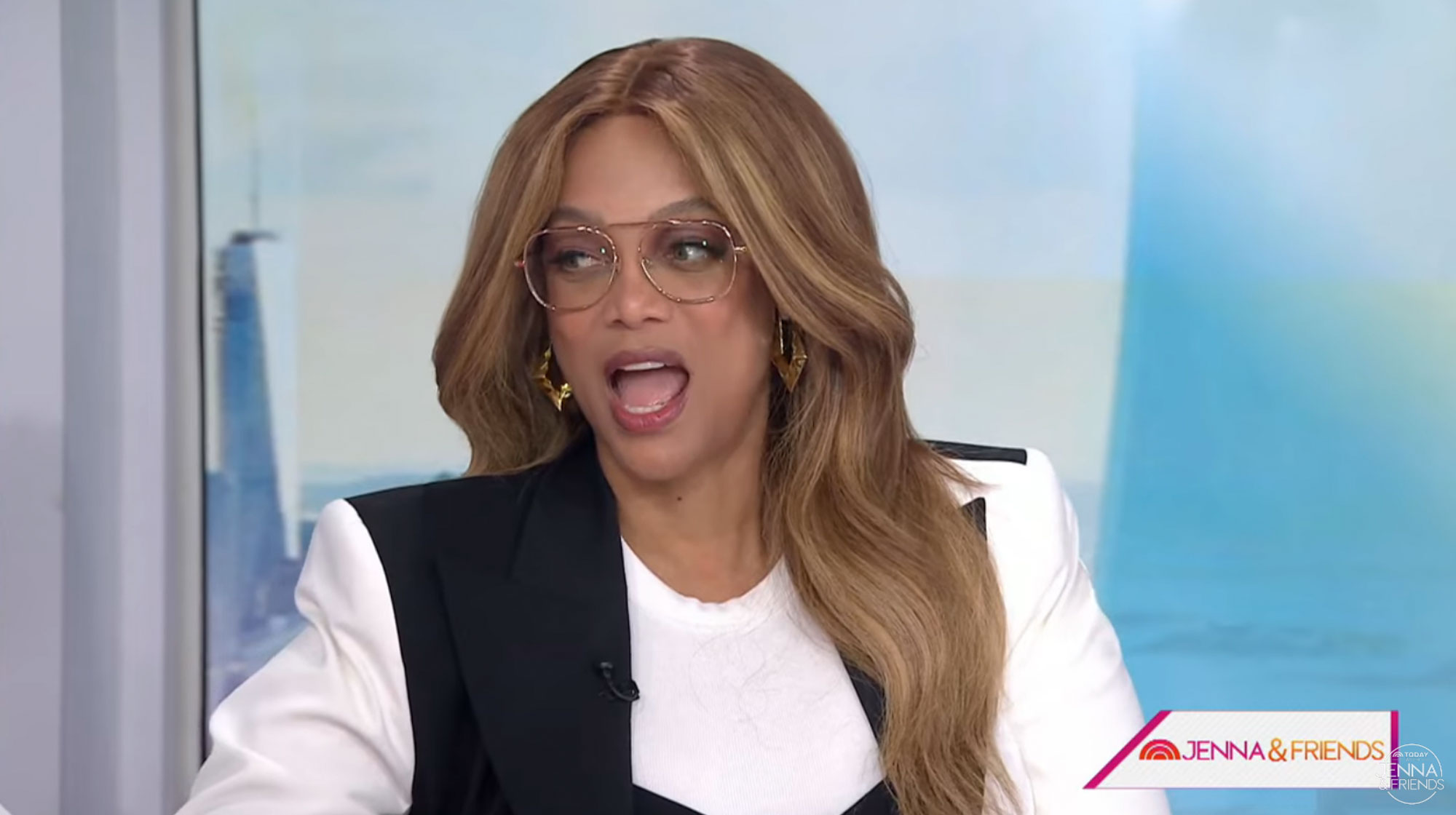 Tyra Banks in black and white at a desk. 