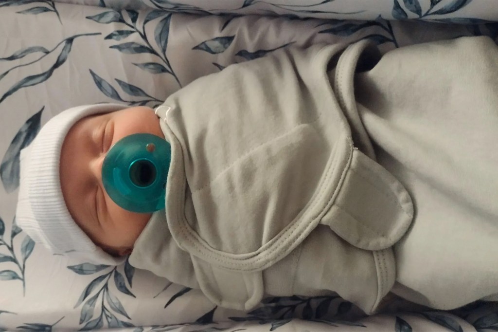 Newborn baby sleeping in a swaddle.