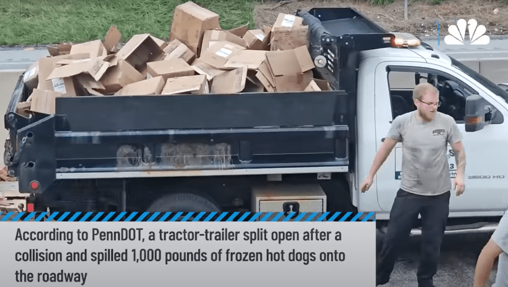 Dump truck filled with cardboard boxes of frozen hot dogs after a spill.