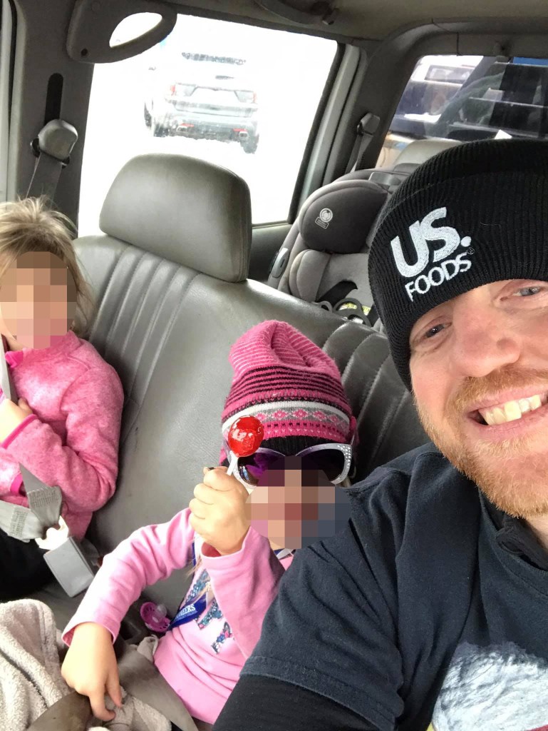 Photo of Clinton Brink with his two daughters in a car.