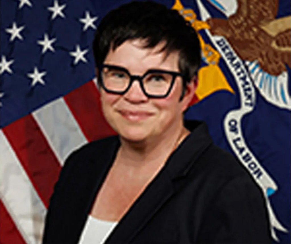 Portrait of Erika McEntarfer, Commissioner of Labor Statistics, in front of an American flag and a state flag.