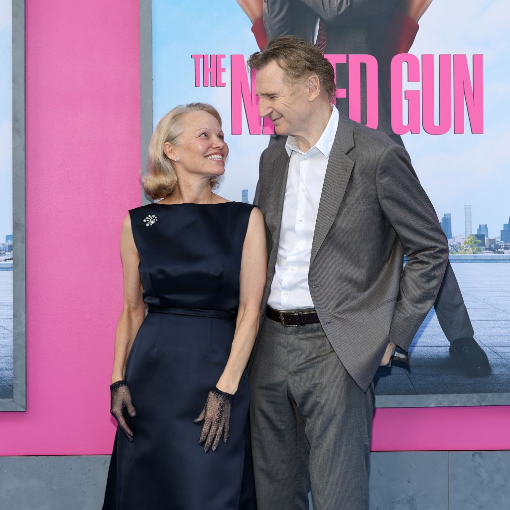 Pamela Anderson in a navy gown with black gloves, Liam Neeson in a grey suit and white shirt.