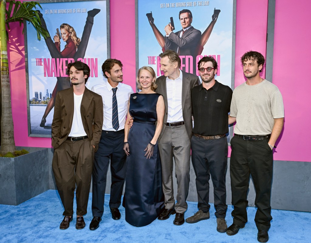 From left: Dylan Lee, in a brown suit and white t-shirt, Brandon Lee, in a white shirt, striped tie and black pants, Pamela Anderson, in a navy blue gown, Liam Neeson, in a grey suit and white shirt, Daniel Neeson, in a black t-shirt and black pants, Micheál Richardson, in a beige t-shirt and black pants.