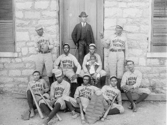 African American baseball players from Morris Brown College, with boy and another man standing at door, Atlanta, Georgia
