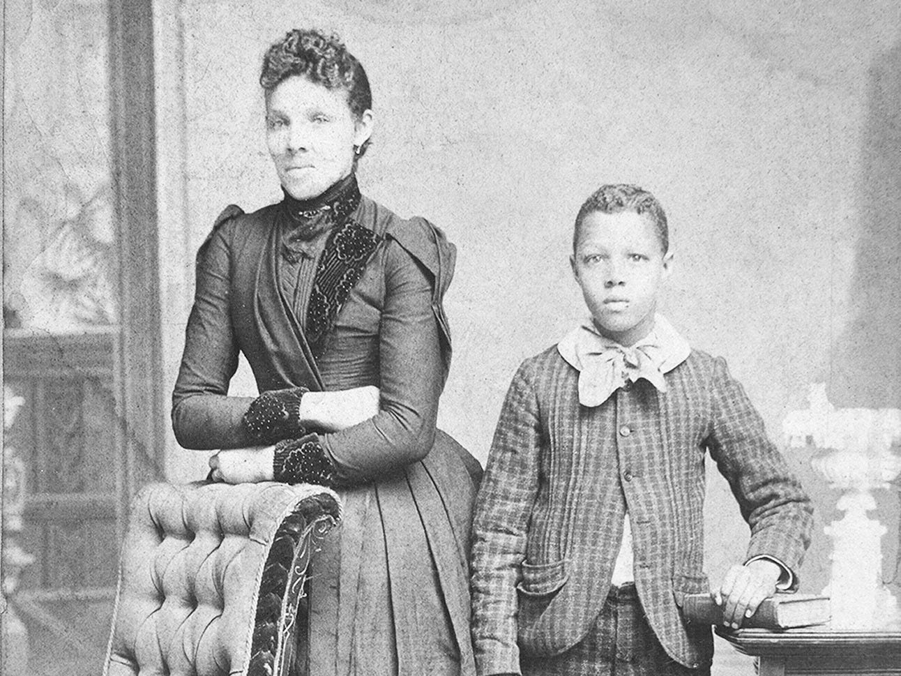 Unidentified standing figures: woman, her folded arms leaning on back of chair, and young man, probably her son, left hand on book, c1890. Additional title: Domestic life. Creator: J. N. Wilson.