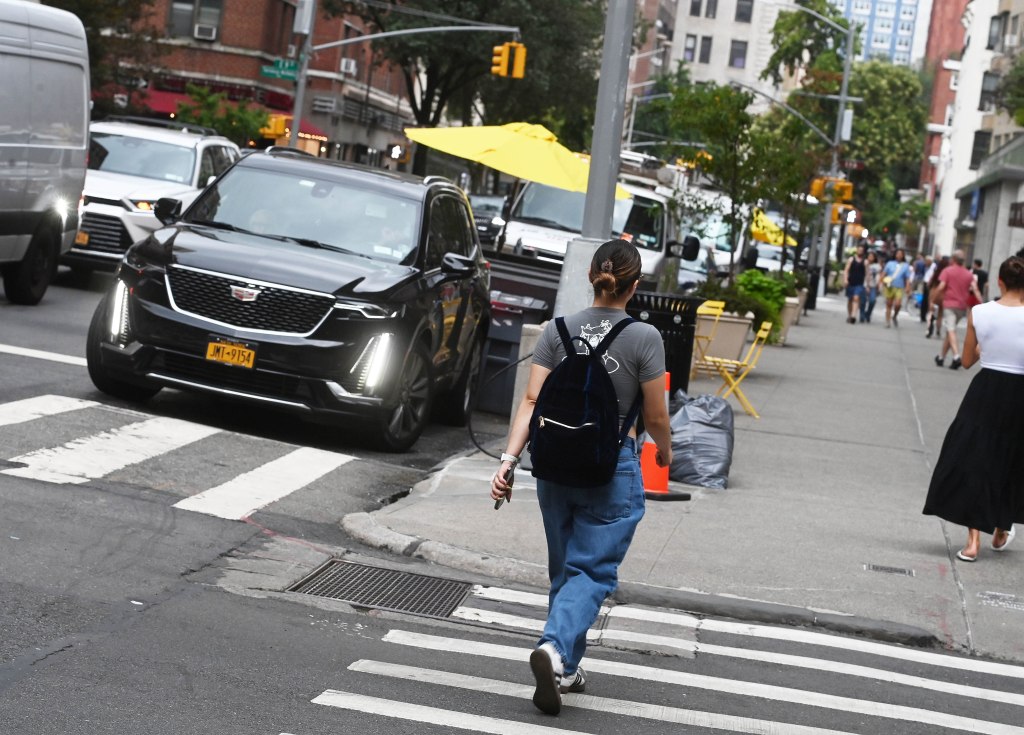 Car parked next to a crosswalk, obstructing pedestrian traffic.