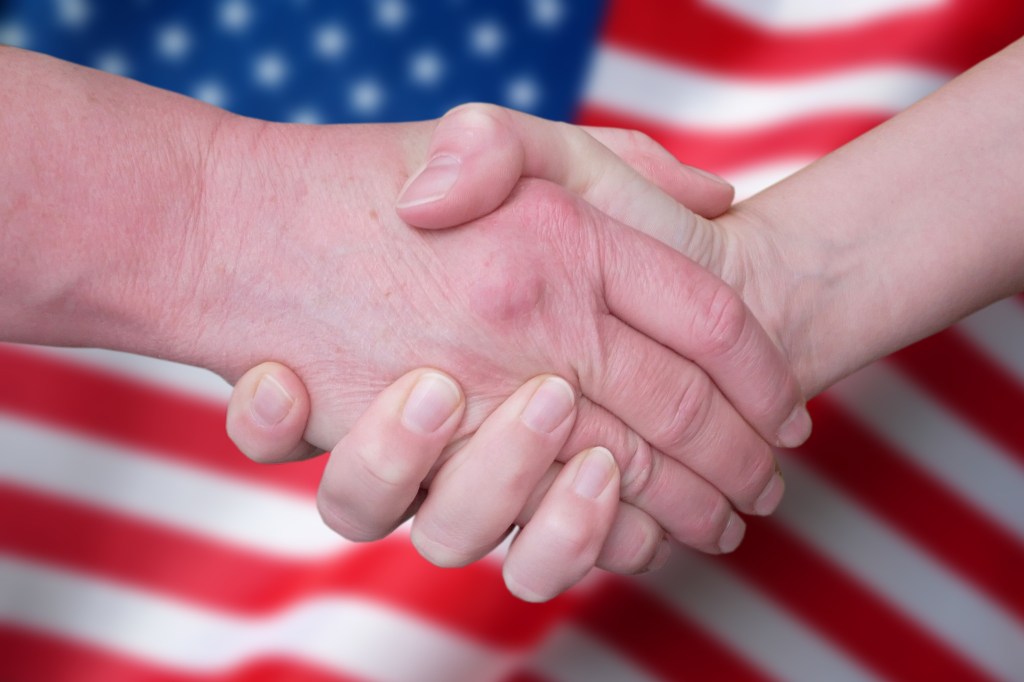 Handshake against a blurred US flag.