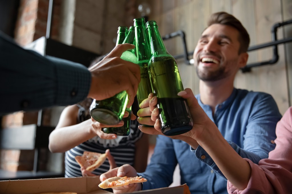 Diverse group of friends toasting with beer bottles.