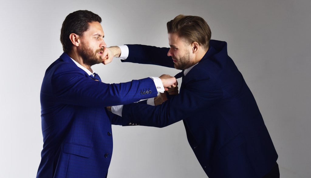 Two businessmen in suits boxing.