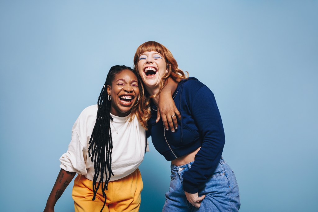 Two interracial best friends laughing together.