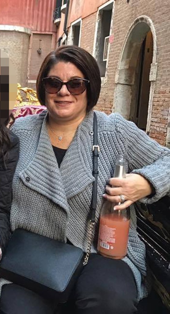 michelle cenci in dark sunglasses grey sweater holding a bottom of what appears to be wine