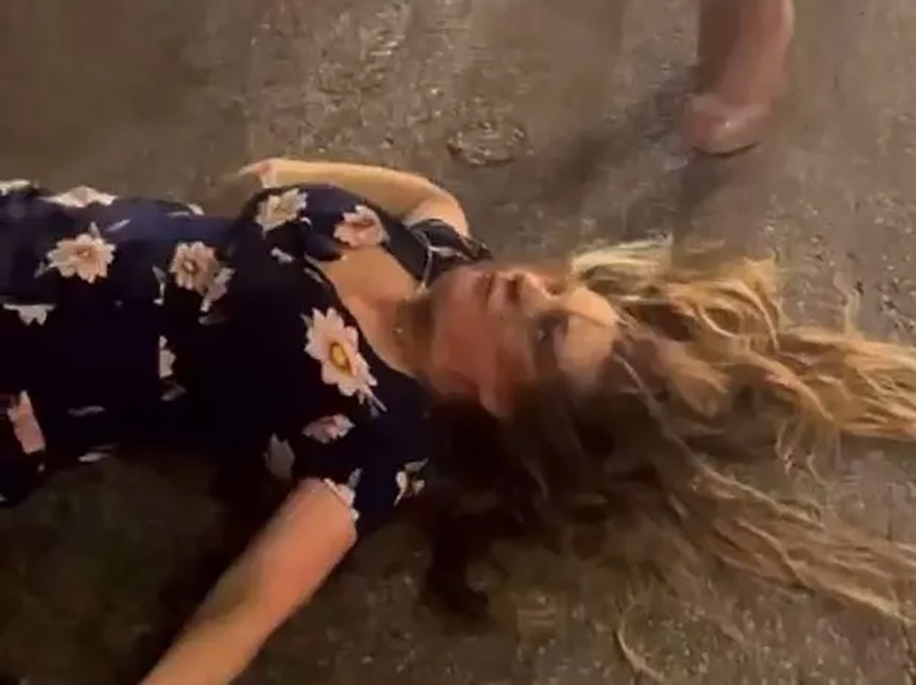 A woman lays knocked out on the ground.