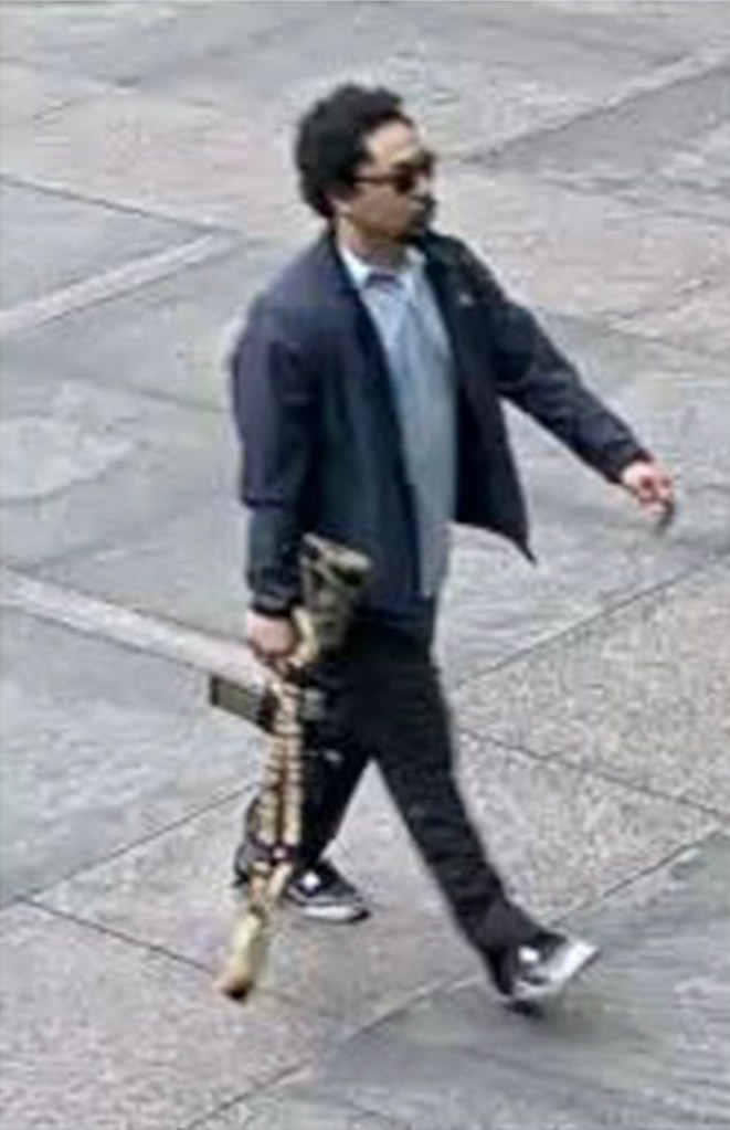 Surveillance image of Shane Tamura carrying a rifle. 