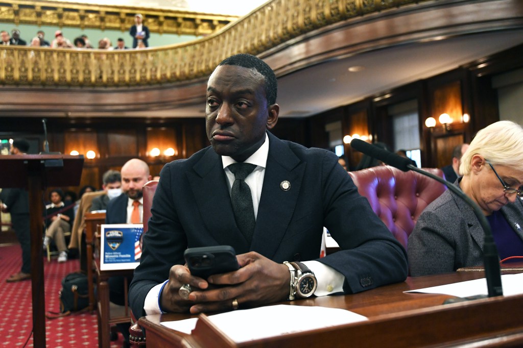 Council member looking at his phone during a city council meeting.