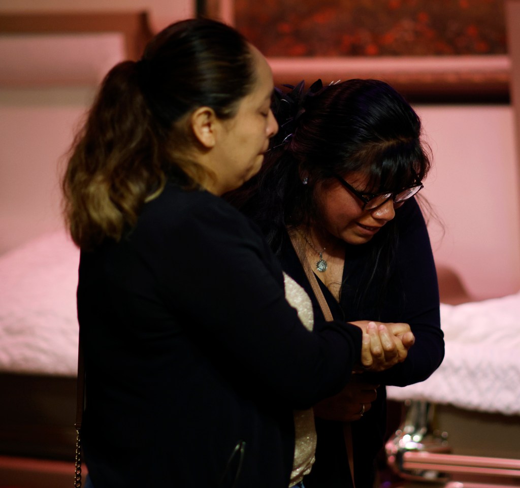 Two women embrace at a wake.