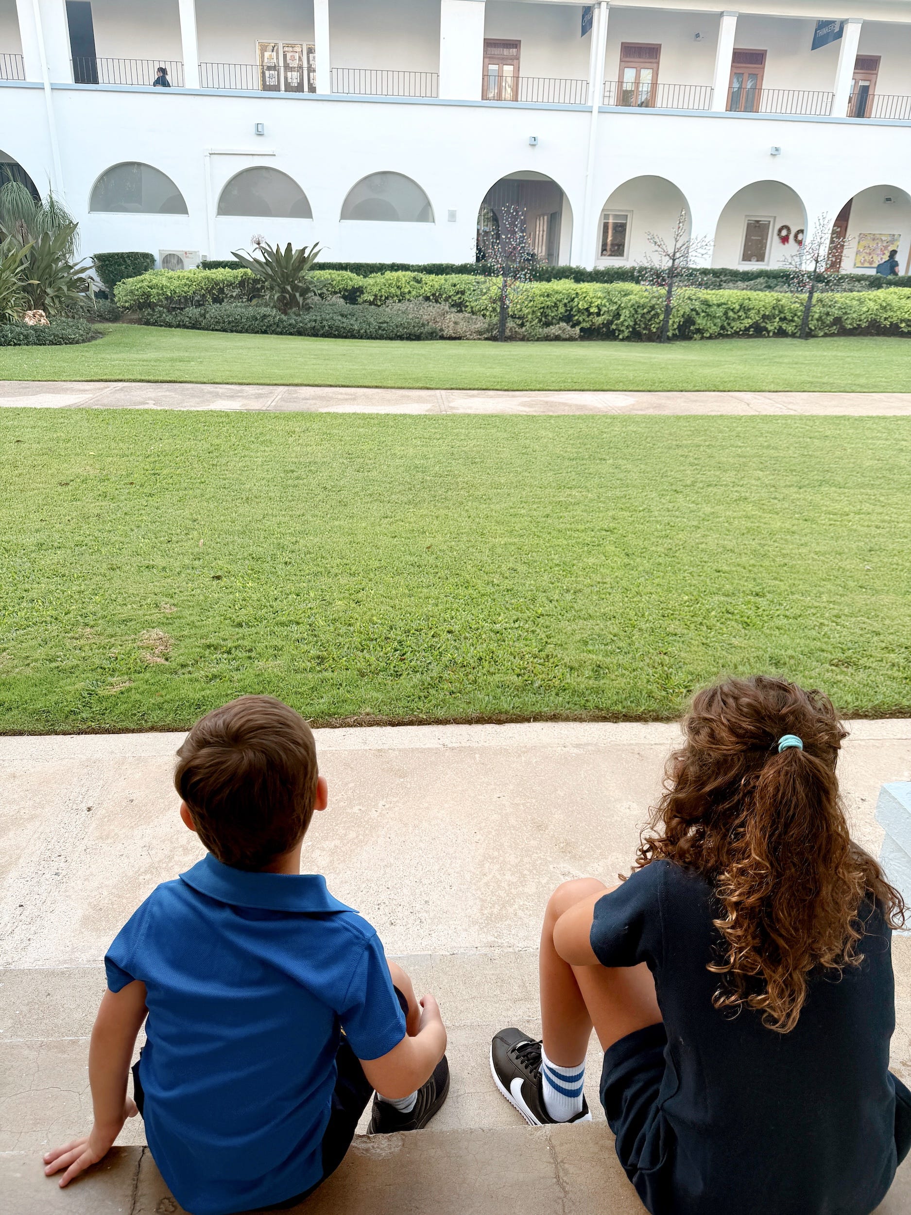 Two children sitting down with their backs to the camera.