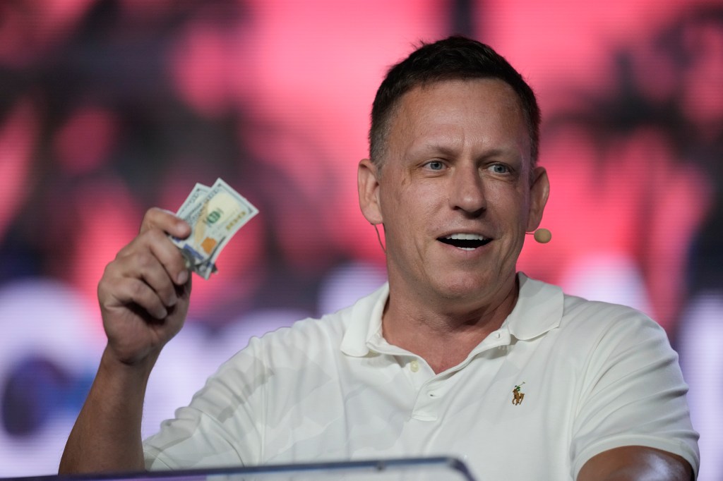 Peter Thiel holding up two hundred-dollar bills at the Miami Bitcoin Conference.
