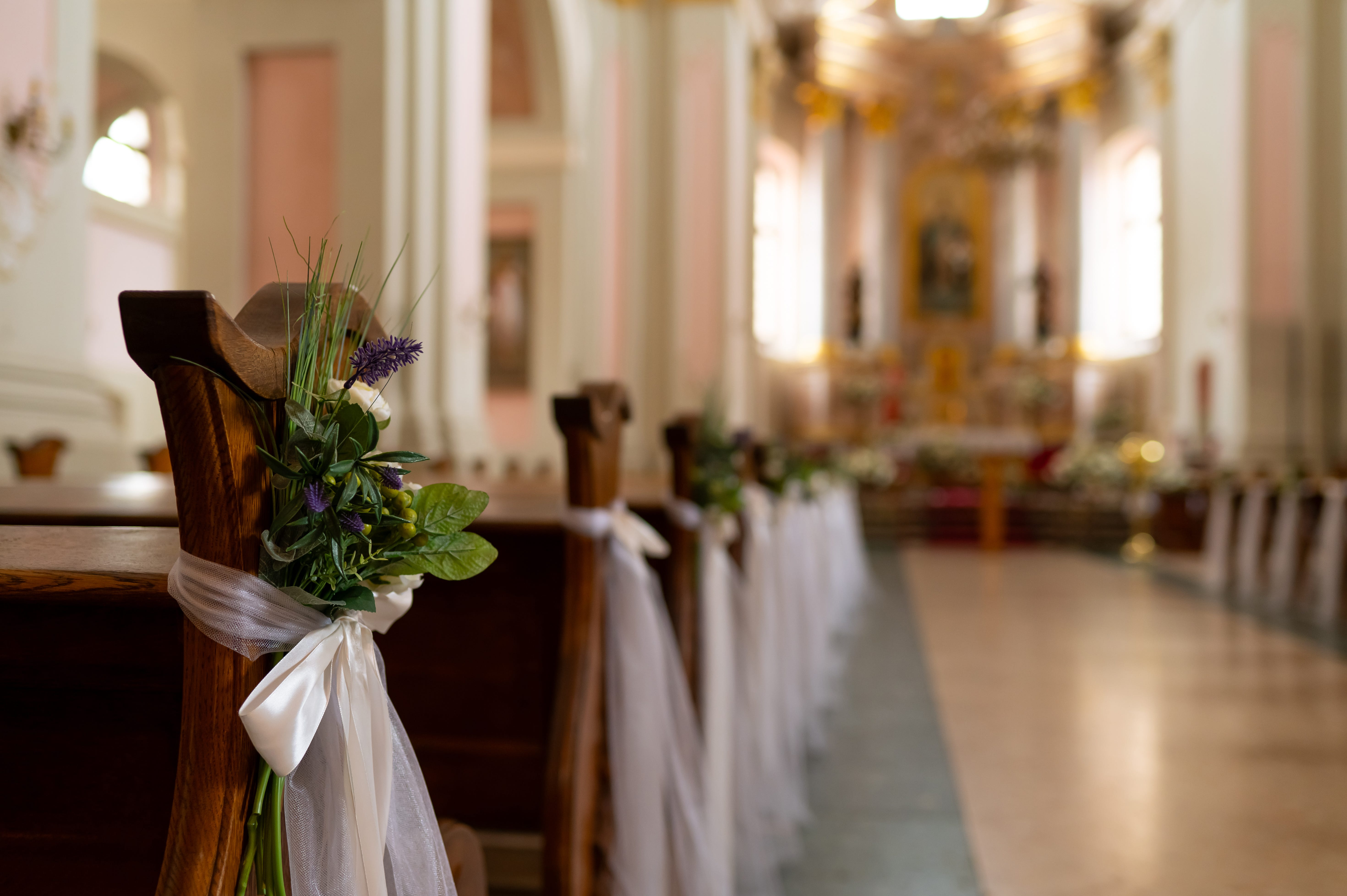 Benches in church with tulle, flowers tied on ends