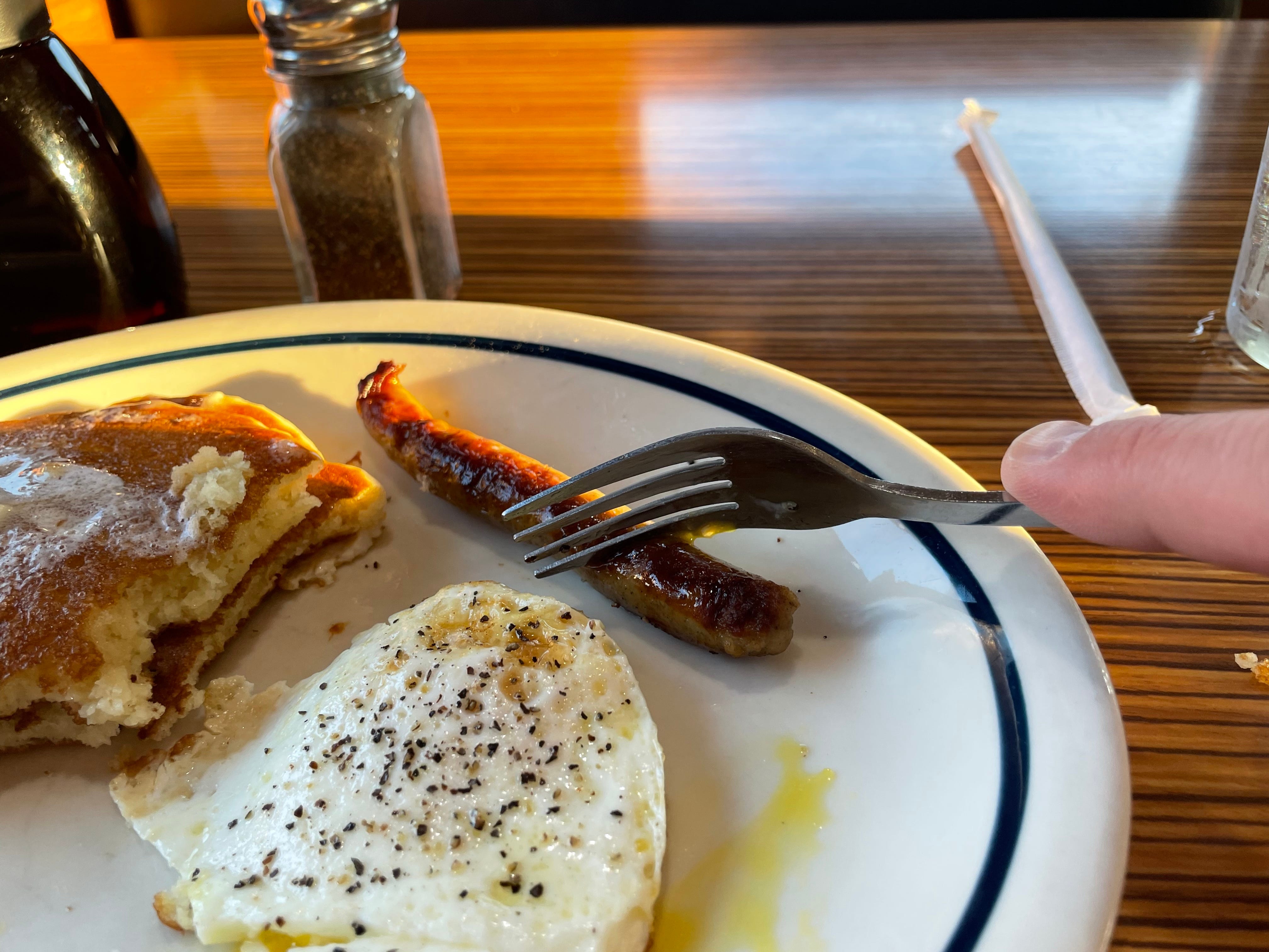 Egg, sausage link and partially eaten pancakes on plate at IHOP