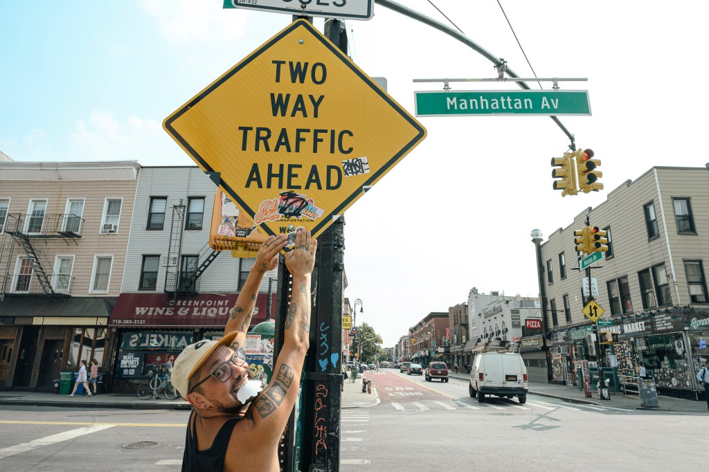 Nick places stickers on a street sign. 
