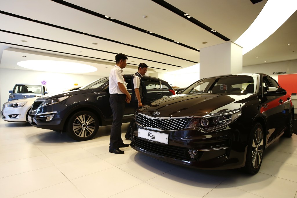 Kia Motors dealership in Seoul, South Korea, with a customer looking at a K5 sedan.