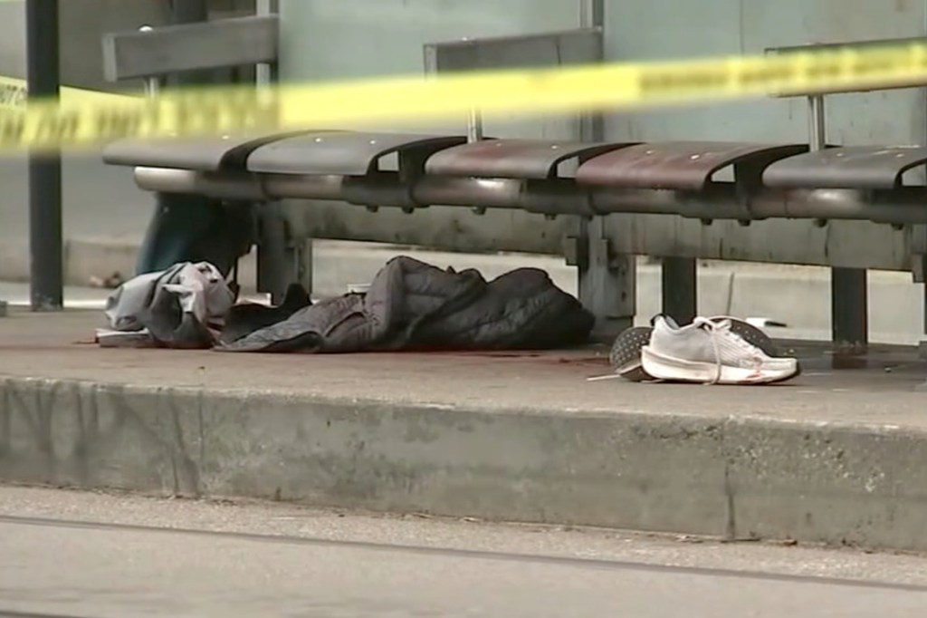 Clothing and a shoe at a bus stop, marked with police tape.