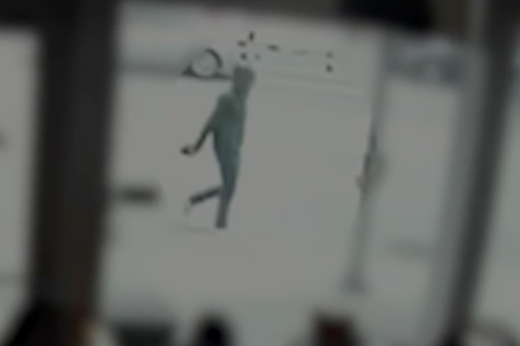 Blurry surveillance footage of a person walking.