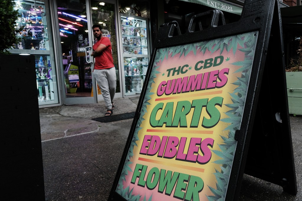 A sign outside a smoke shop advertises THC and CBD gummies, carts, edibles, and flower.