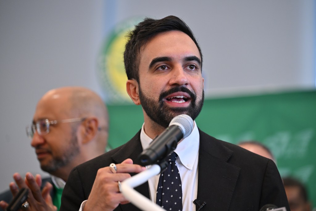 Zohran Mamdani speaking at a podium.