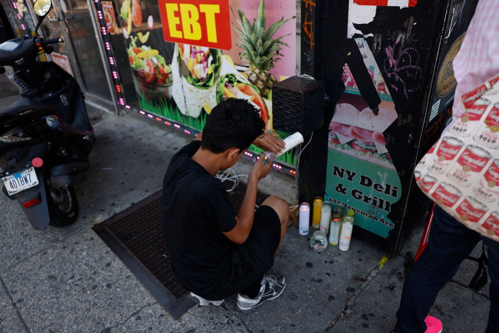Person lighting candles at a makeshift memorial.
