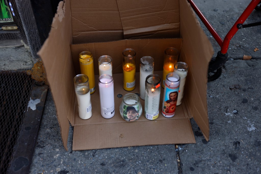 Makeshift memorial with lit candles in a cardboard box.