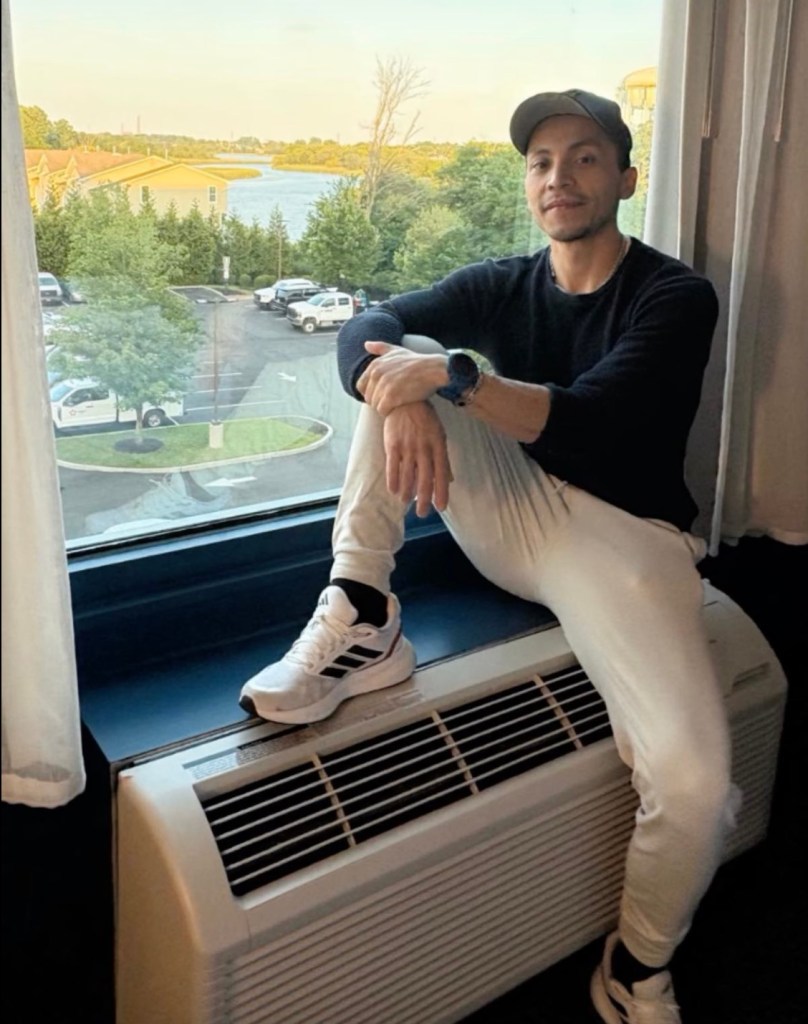 Man sitting on windowsill, looking at the camera.