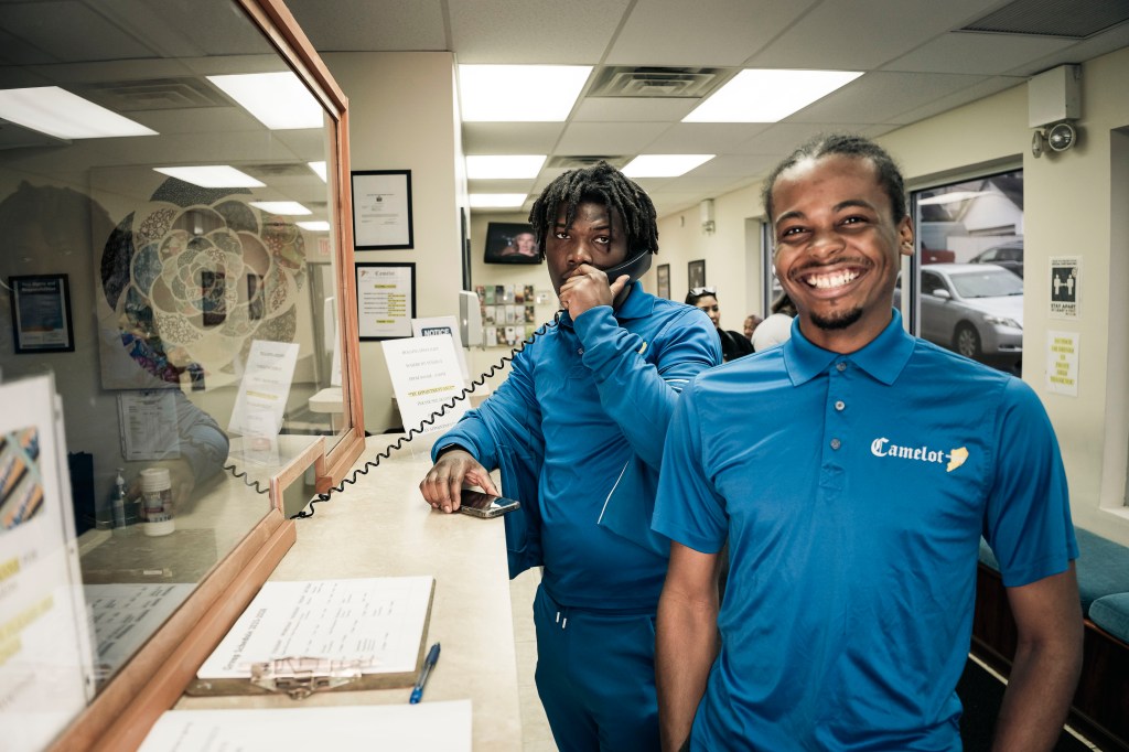 Two young men in blue Camelot Counseling polo shirts at the reception desk.