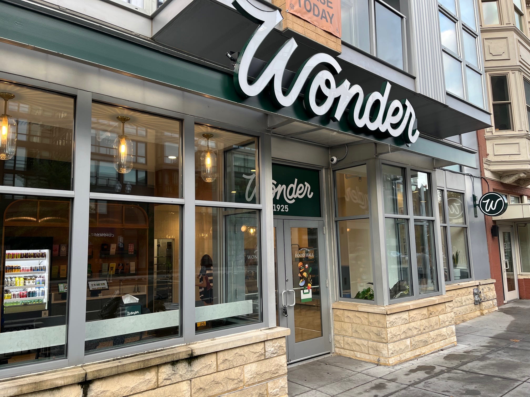 The entrance to a Wonder food hall in Washington, DC, with a white, lighted "Wonder" sign above the front door.